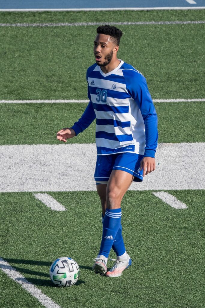 Anderson dribbling the soccer ball on the field for Drake University in a soccer match.