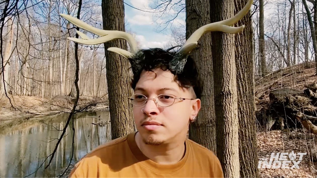 Shoesoup, wearing deer antlers on his head, looks around the woods
