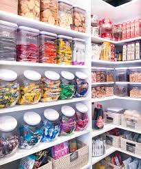 An organized pantry with color coded plastic containers labeled with the kinds of food that are inside each one.