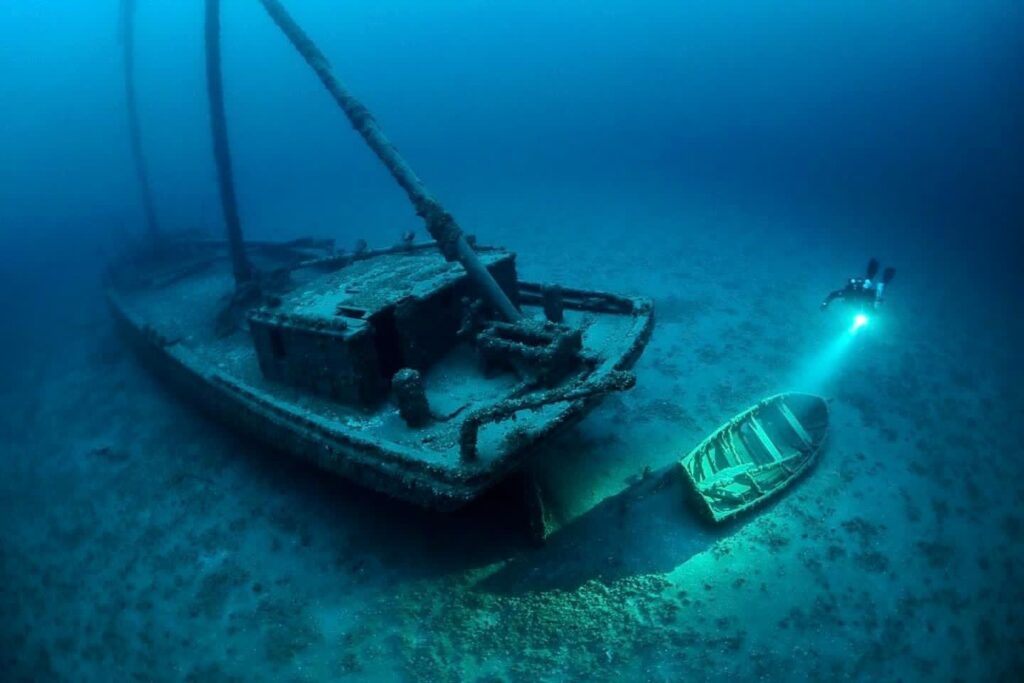Diver swimming past a shipwreck.
