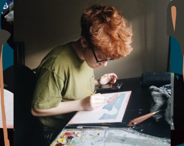 A person sitting at a desk painting on paper.