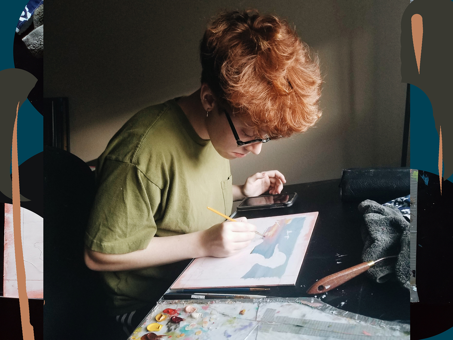 A person sitting at a desk painting on paper.