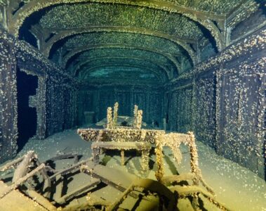 Interior of a shipwreck with scattered tables and chairs.