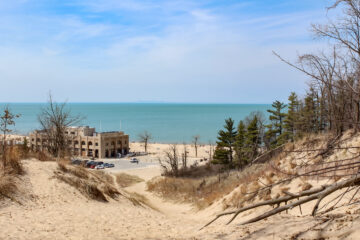 An image on top of a sand dune, overlooking the Indiana Dunes National Park Pavilion on the beach with Lake Michigan in the background.