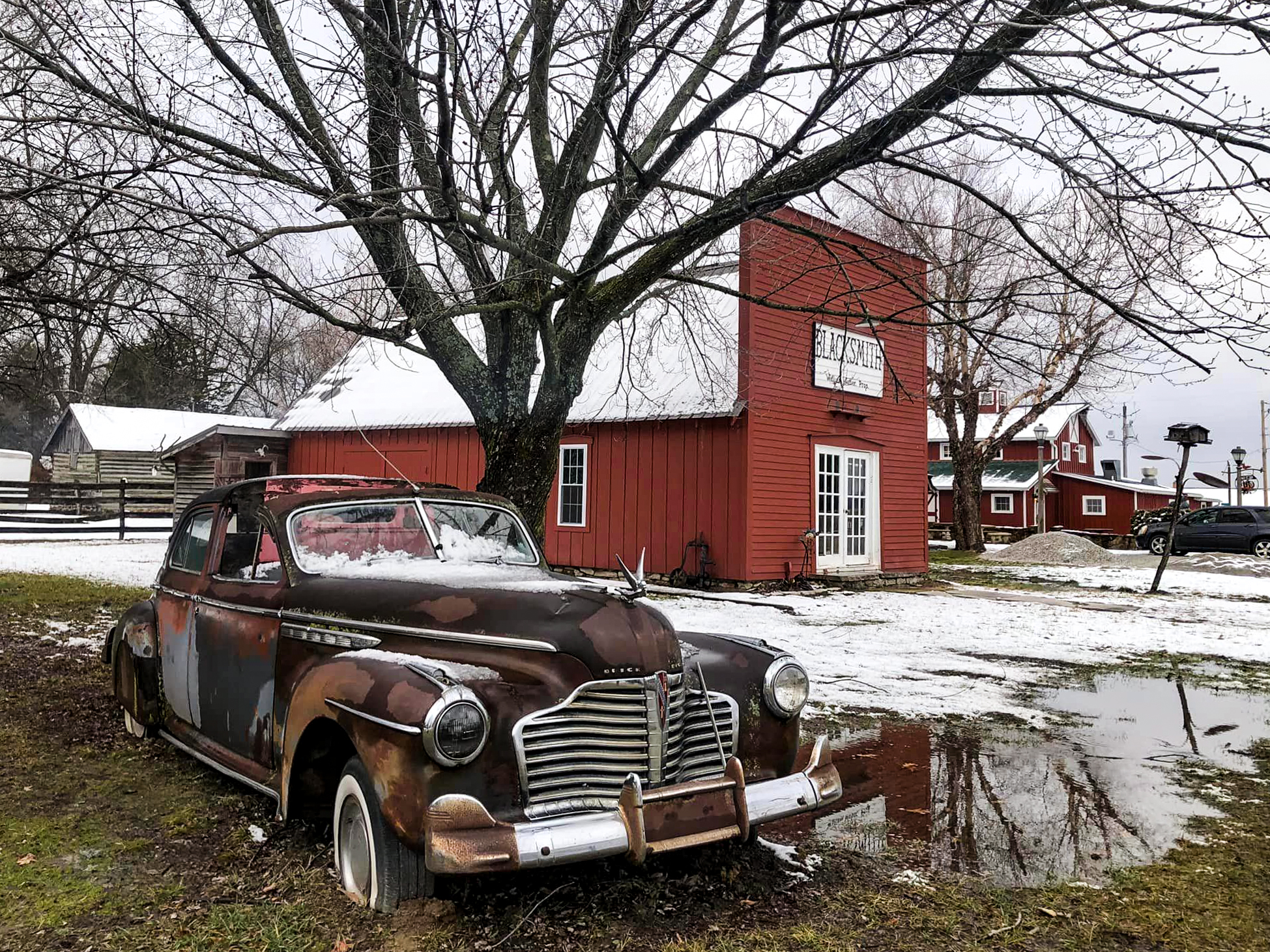 Lowell Davis’s grandfather's original blacksmith shop that Lowell had transferred to Red Oak II. Lowell Davis’s old automobile is also pictured.