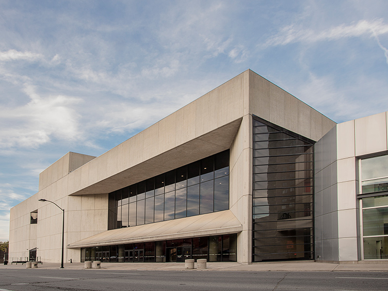 A photo outside the Des Moines Civic Center. The building is large with harsh cement angles and rows of large windows.