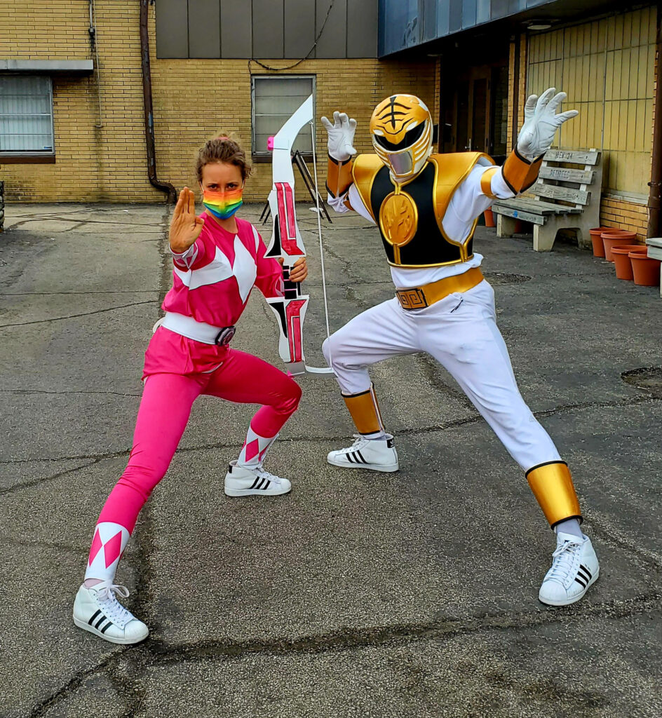 Rezell strikes a pose in a 90s White Power Ranger cosplay with the Pink Ranger at his side. 
