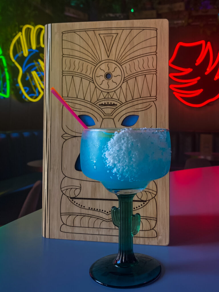 A blue drink in a cactus-themed margarita glass.